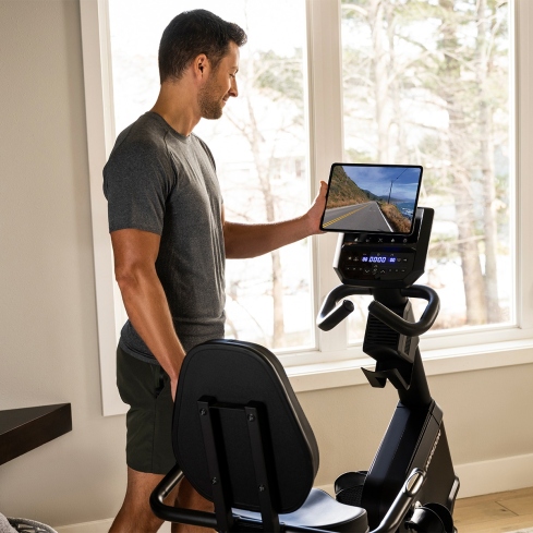 Hombre entrenando con iPad y Virtual Active en la Bicicleta est&aacute;tica reclinada Horizon Fitness 5.0R con dise&ntilde;o ergon&oacute;mico y consola digital